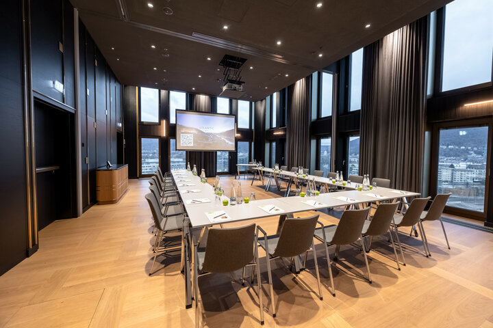 Moderner Konferenzraum im ATLANTIC Hotel Heidelberg mit U-förmiger Bestuhlung, großen Fenstern und Präsentationsleinwand.