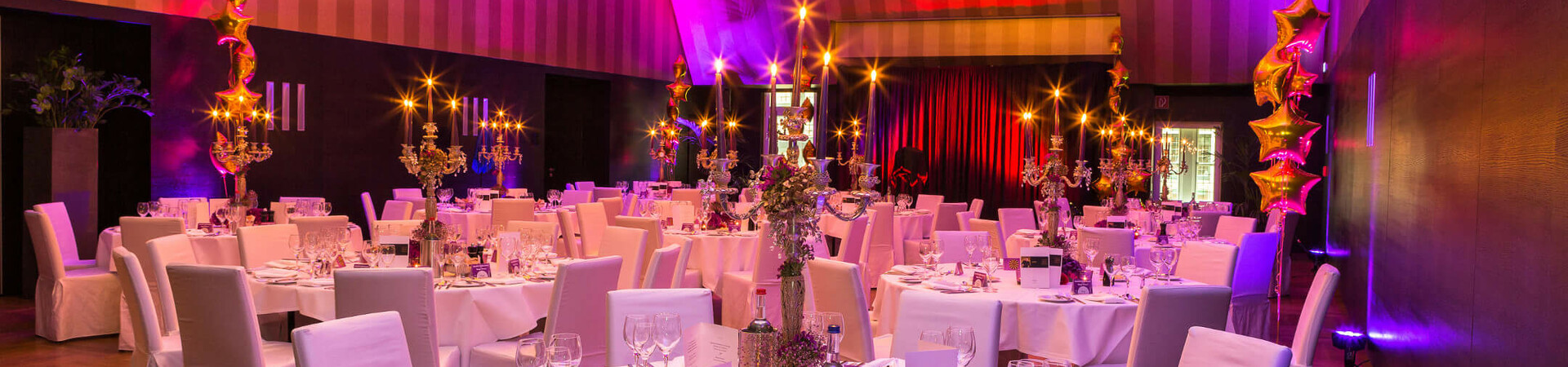 Elegant, festively lit banquet hall with round tables set in white at the ATLANTIC Grand Hotel Bremen.