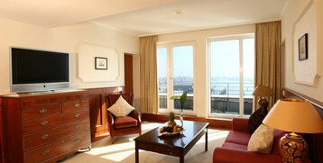 Living room of the Gorch Fock Suite with a sofa and flatscreen TV in the ATLANTIC Hotel Wilhelmshaven 