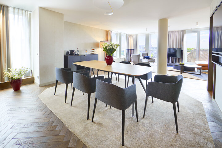 Bright, modern hotel room at the ATLANTIC Grand Hotel Bremen with dining table, chairs and large windows.