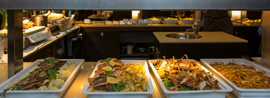 Buffet im ATLANTIC Grand Hotel Bremen mit verschiedenen Speisen in Schalen, darunter Fleisch, Kartoffeln und Gemüse.