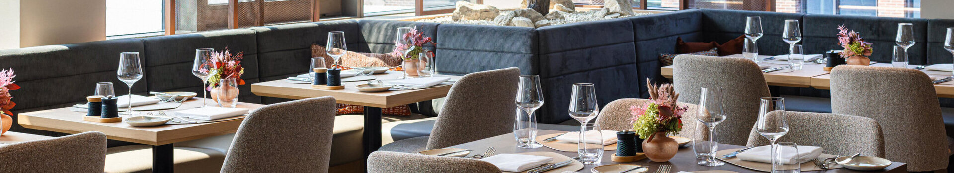Das Restaurant 4FRANK mit Fensterfront und Baum im Restaurant.