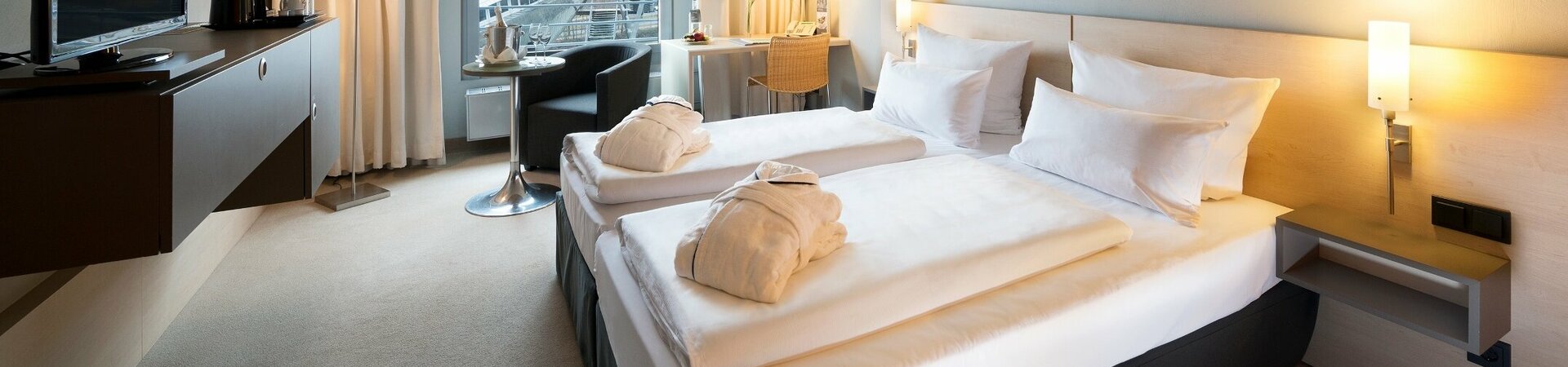Comfort Doppelzimmer mit Blick auf das Universum Bremen Modernes Hotelzimmer mit Doppelbett, Schreibtisch, Sessel, großem Fenster und TV im ATLANTIC Hotel Universum Bremen.
