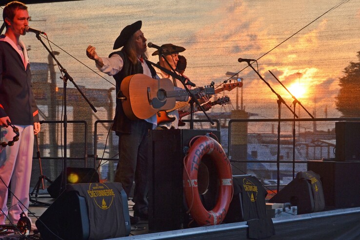 Live band on stage at sunset, musicians in maritime clothing, the harbor of Vegesack in the background.