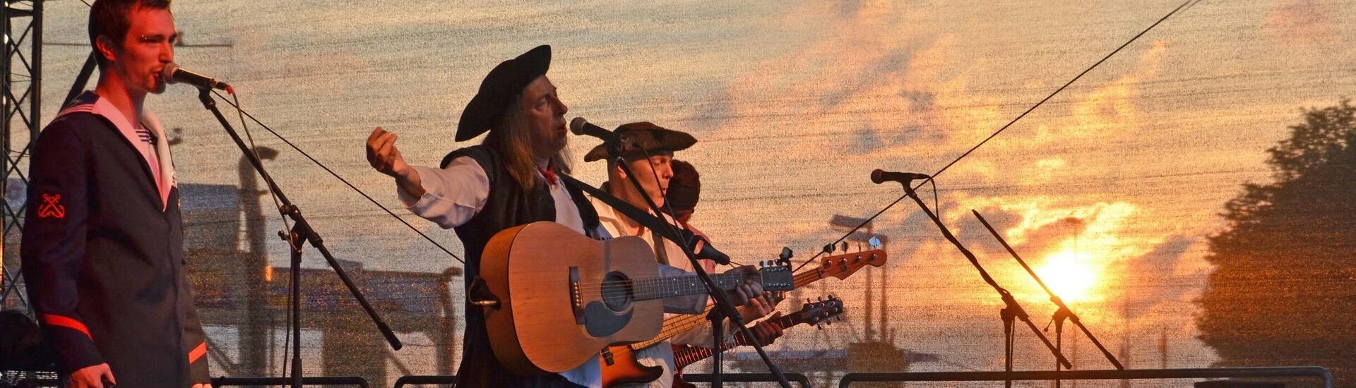 Band during a performance at the Festival Maritim in Bremen Vegesack Live band on stage at sunset, musicians in maritime clothing, the harbor of Vegesack in the background.