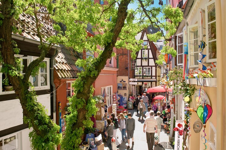 Lively, picturesque alley in Bremen with half-timbered houses, stores and colorful decorations under a blue sky.