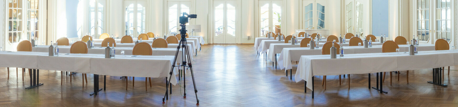 Heller, eleganter Ballsaal im ATLANTIC Grand Hotel Travemünde mit Tischen, Stühlen und Kronleuchter.