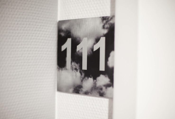 Door sign with the room number 111 in front of a cloudy background in the ATLANTIC Hotel Airport Bremen.