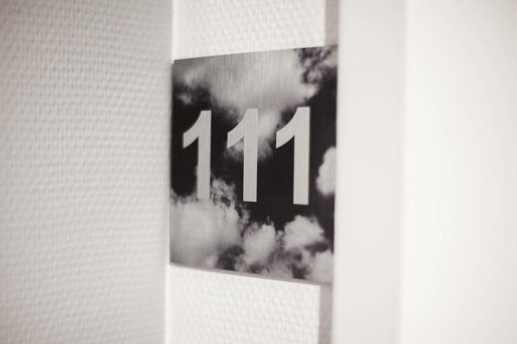 Door sign with the room number 111 in front of a cloudy background in the ATLANTIC Hotel Airport Bremen.