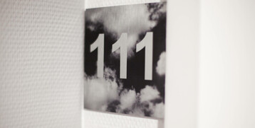 Türschild mit der Zimmernummer 111 vor wolkigem Hintergrund im ATLANTIC Hotel Airport Bremen.