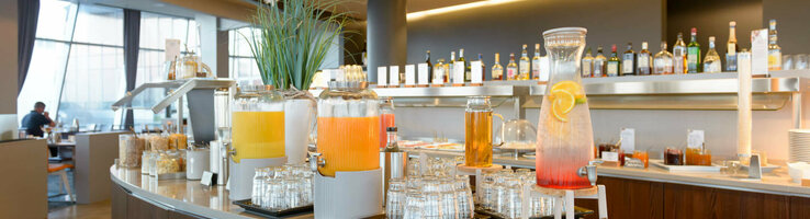 Drinks bar in the ATLANTIC Hotel Sail City with juice dispensers and glasses, modern interior in the background.