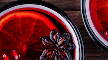 Zwei Becher mit rotem Glühwein und einer Orangenscheibe