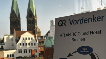 Die Auszeichnung des Vordenker Preises 2025 auf einer Fensterbank, im Hintergrund der Ausblick aus dem Hotel mit dem Blick auf den Bremer St. Petri Dom.