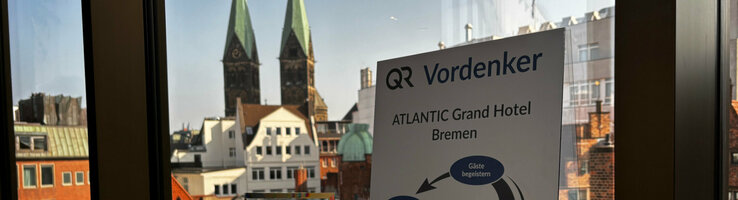 Die Auszeichnung des Vordenker Preises 2025 auf einer Fensterbank, im Hintergrund der Ausblick aus dem Hotel mit dem Blick auf den Bremer St. Petri Dom.
