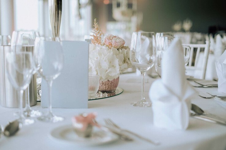 Elegant table setting with white flowers, wine glasses and folded cloth napkins at the ATLANTIC Hotel Galopprennbahn.