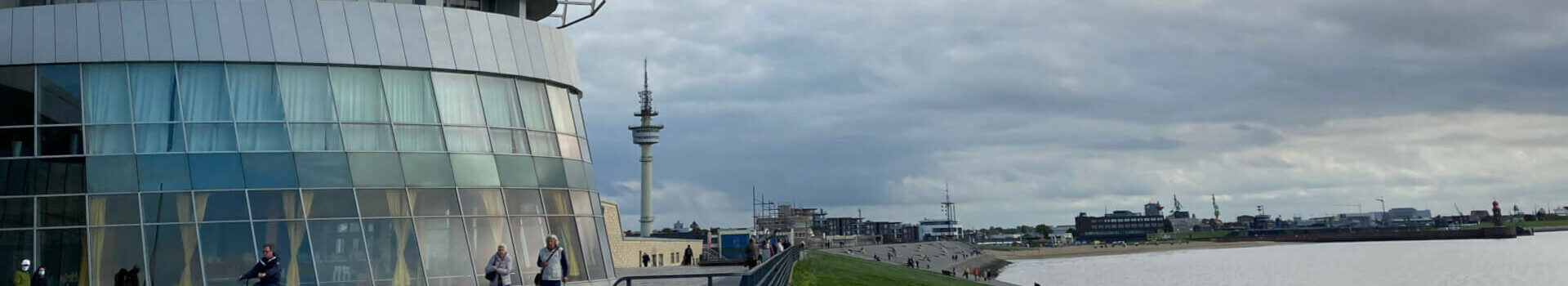 ATLANTIC Hotel Sail City in Bremerhaven, modern building on the waterfront, walkers and cyclists on the forecourt.