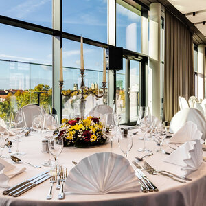 Elegant table setting at the ATLANTIC Hotel Münster with a view of the city through large windows.