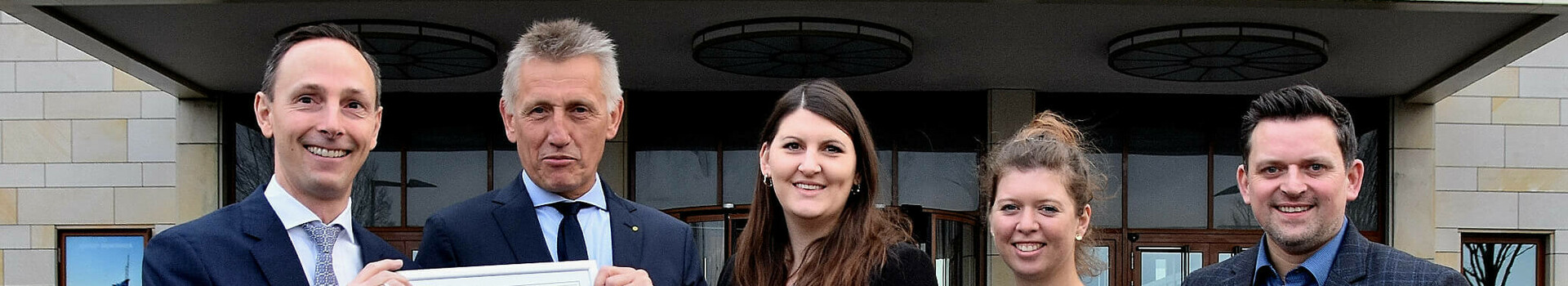 Fünf Personen vor dem ATLANTIC Hotel Wilhelmshaven halten eine Urkunde und eine Auszeichnung.
