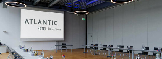 Moderner Konferenzraum im ATLANTIC Hotel Universum mit U-förmiger Tischanordnung und großen Fenstern.