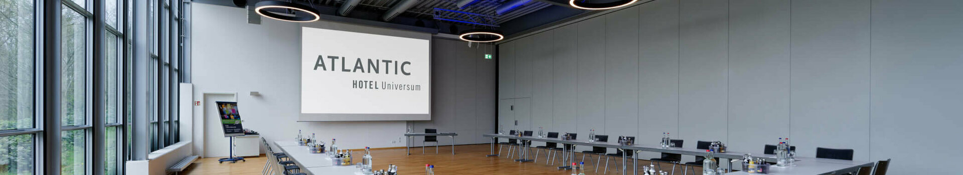 Moderner Konferenzraum im ATLANTIC Hotel Universum mit U-förmiger Tischanordnung und großen Fenstern.