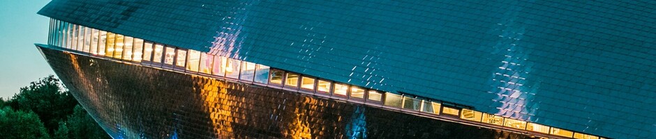 Futuristisches Gebäude des Universum Bremen bei Dämmerung, mit leuchtenden Fenstern und spiegelnder Fassade.