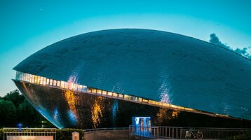 Futuristisches Gebäude des Universum Bremen bei Dämmerung, mit leuchtenden Fenstern und spiegelnder Fassade.
