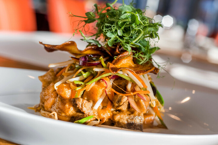 Speisen und Getränke | ATLANTIC Hotel Universum Bremen Gourmetgericht mit Gemüse, Sprossen und Kräutern kunstvoll auf weißem Teller im ATLANTIC Hotel Universum Bremen.