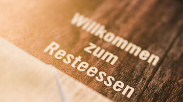 Wilkommen zum Resteessen im ATLANTIC Hotel Sail City in Bremerhaven Tischset mit Besteck und der Aufschrift „Willkommen zum Resteessen“ im ATLANTIC Hotel Sail City, Bremerhaven.