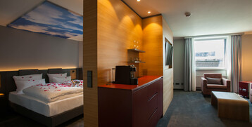 Modernes Hotelzimmer mit Doppelbett, Sitzecke, großem Fenster und Kaffeemaschine im ATLANTIC Hotel Airport Bremen.