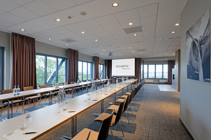 ATLANTIC Hotel Airport U-Form Conference Bright conference room with U-shaped seating, large windows and projection screen at the ATLANTIC Hotel Airport Bremen.