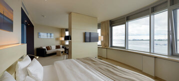 gesamtes Studio Zimmer mit Schlafbereich, einer Sitzgelegenheit und die Aussicht auf die Weser| ATLANTIC Hotels Sail City