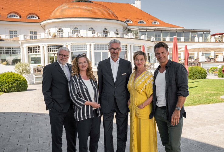 Gruppe von fünf Personen vor dem ATLANTIC Grand Hotel Travemünde bei sonnigem Wetter.