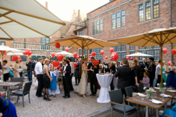 Group celebrates wedding in the courtyard of the ATLANTIC Grand Hotel Bremen, with red balloons and elegant guests.