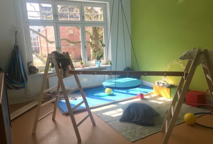 Heller Spielraum mit Klettergerüst, Schaukel und bunten Spielbällen im ATLANTIC Hotel Airport Bremen.