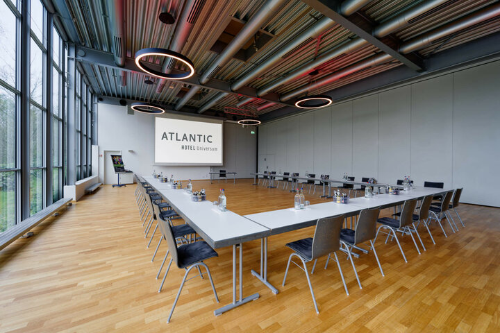 Tagungsraum im ATLANTIC Hotel Universum Bremen mit U-förmiger Bestuhlung, Holzboden und großen Fenstern.