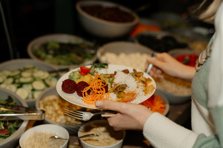 Person hält Teller mit vielfältigem Buffetessen im ATLANTIC Hotel Münster.