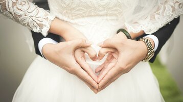 Celebrate your wedding at the ATLANTIC Hotel Landgut Horn Bride and groom form a heart with their hands in front of a lace dress, symbolizing love and solidarity.