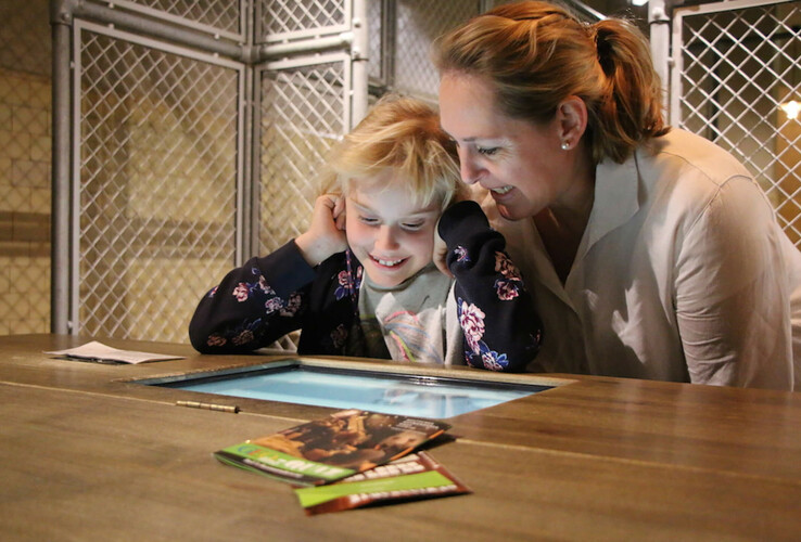 Kind und Erwachsene betrachten interaktiv einen Bildschirm im ATLANTIC Hotel Sail City in Bremerhaven.