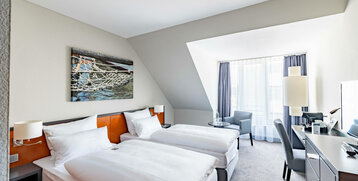 Helles Hotelzimmer mit zwei Einzelbetten, modernem Dekor und großem Fenster im ATLANTIC Hotel Vegesack, Bremen.