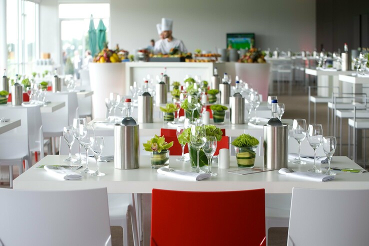 Modernes Restaurant im ATLANTIC Hotel, elegant gedeckte Tische mit Blumen und Gläsern, im Hintergrund ein Koch.