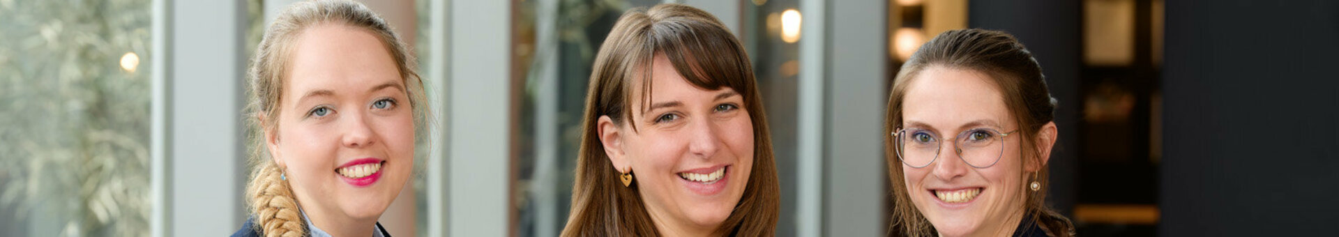 Das Veranstaltungsverkaufsteam in Businesskleidung stehen in einem modernen, hellen Hotellobby-Bereich.