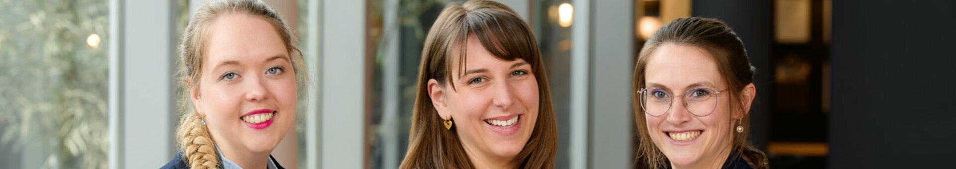The event sales team in business attire stand in a modern, bright hotel lobby area.