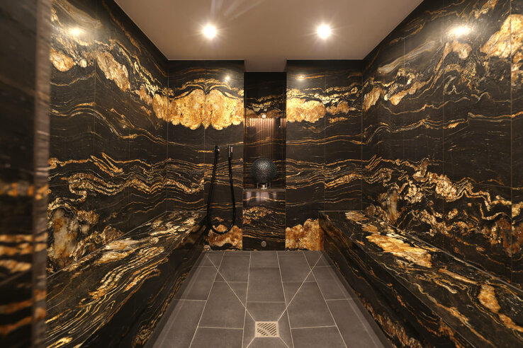 Elegantes Dampfbad mit dunklem, goldgemustertem Marmor im ATLANTIC Hotel Heidelberg.